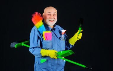 Professional cleaning service. Cleaner with sweeping tools and cleaning supplies. Cleaning agency. Smiling bearded man in uniform with broom, dustpan and brush for carpet. Cleaning time. Housekeeping.