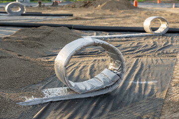 Construction photo of a roll of flat panel drainage pipe being installed on a synthetic turf multi...