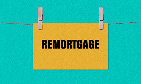REMORTGAGE Symbol. Concept words REMORTGAGE on Yellow Rectangle Paper Hanging on a Wooden Clothespin Green Background. Business REMORTGAGE Concept with Copy Space