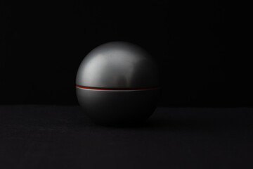 Perfume in a round bottle and a bird feather on a dark background