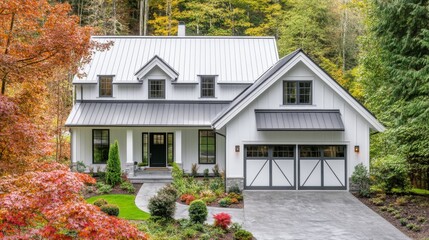 White farmhouse with a gray roof and wide front windows. Features a central entrance and garage, framed by colorful, manicured plants.