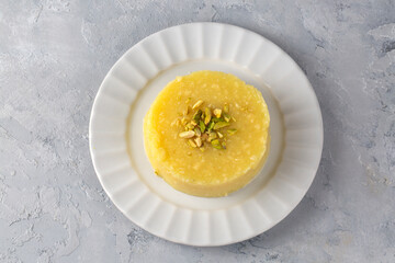Sweet yellow Turkish dessert cheese halva Hosmerim on the white plate in the kitchen.