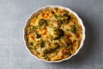 Casserole Cauliflower and broccoli baked with cheese sauce in a pot close-up on a wooden table. Horizontal top view from above. Broccoli gratin.