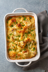 Casserole Cauliflower baked with cheese sauce in a pot close-up on a wooden table. Horizontal top...