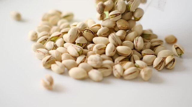 Close-up of pistachio nuts rotating on the white table, Pistachio Nuts.