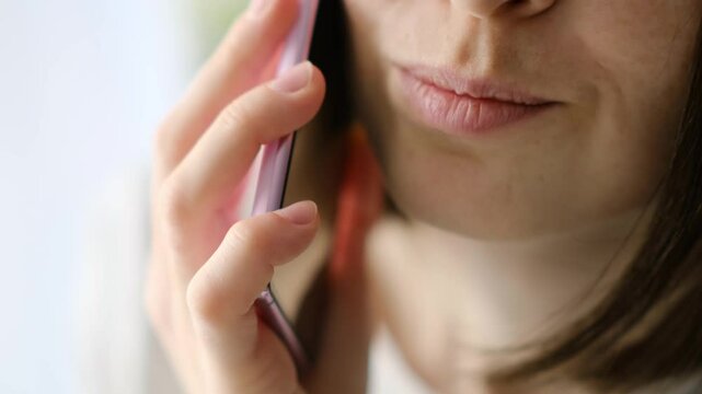 Woman talking on cellphone and smiling, closeup, 4k closeup footage of woman face while talking by cell phone.