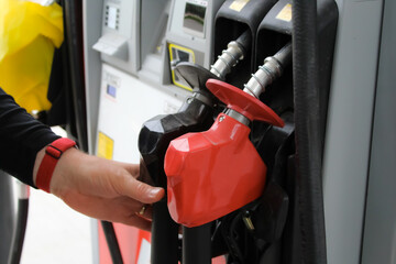 a person reaching for a fueling nozzle at a gas station. transportation, economy, and energy industry design element.