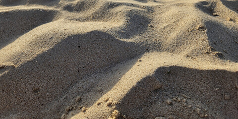 close-up view of textured sand. undulating patterns and shadows with light effect. vacation theme. background or wide panoramic banner with copy space