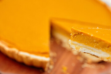 Delicious pumpkin pie with a golden crust, showcasing a slice being lifted, highlighting the creamy...