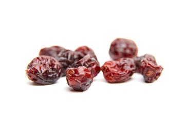 Dried red cranberries scattered on a white background, showcasing their wrinkled texture and rich...