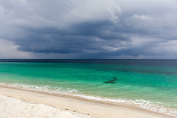 A tranquil beach in Thailand with crystal clear emerald green waters and dramatic storm clouds...
