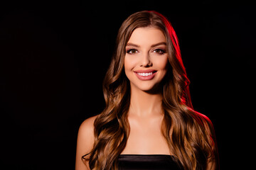 Naklejka premium Portrait of joyful lady with brunette wavy haircut smiling wearing black top dress on dark background