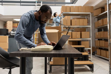 African american staff member overseeing hand packing goods in inventory room of a small business,...