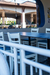 Empty outdoor dining area with blue cushioned chairs and dark table