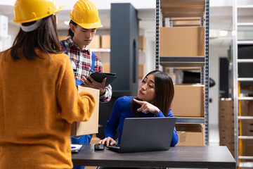 Asian staff members at a fulfillment center printing invoices and prepares packages with bar codes and shipping labels. Small business handles local delivery and in house order processing.
