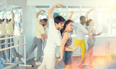 Group of men and women in sportswear learning to dance latin dances in a dance studio