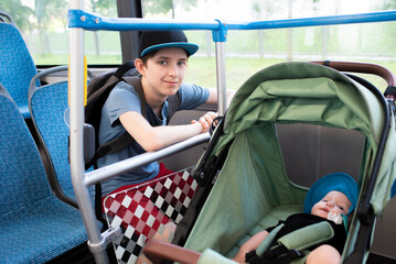 Children on a bus in summer. A teenage boy sits by the window, a baby sits in a stroller, brothers...