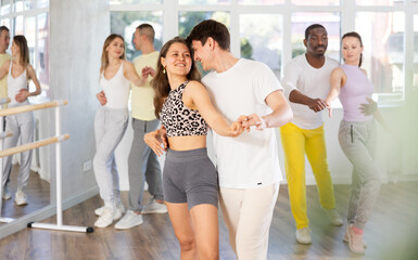 Naklejka premium Group of men and women in sportswear learning to dance latin dances in a dance studio