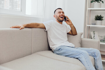 Happy man talking on the phone, expressing emotions while enjoying a relaxing moment at home,...