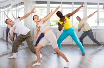 Active female Hip-hop dancers exercising dance moves in modern studio with multinational group