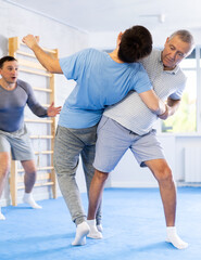 Mature man throws young guy to the mat - two men of different ages in judo sparring