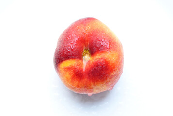 Flat peach isolated on white background. One fig peach in water drops. Fresh tasty peach