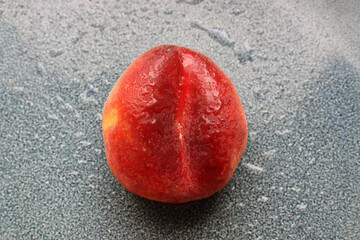 Red ripe flat peach on blue plate. One fig peach in water drops. Fresh tasty peach