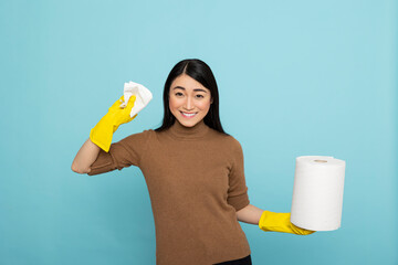 Asian housekeeper wearing rubber gloves holding paper towel, standing ready for daily chores....