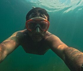 Man swimming underwater in the lake of Levico in Trentino, Northern Italy. The man is forty years...