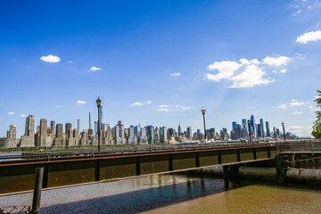 Skyline vista showcasing a cityscape from across a bridge, under a bright sky. The city buildings...