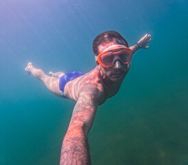 Man swimming underwater in the lake of Levico in Trentino, Northern Italy. The man is forty years...