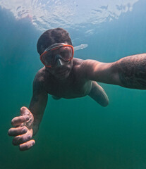Man swimming underwater in the lake of Levico in Trentino, Northern Italy. The man is forty years...