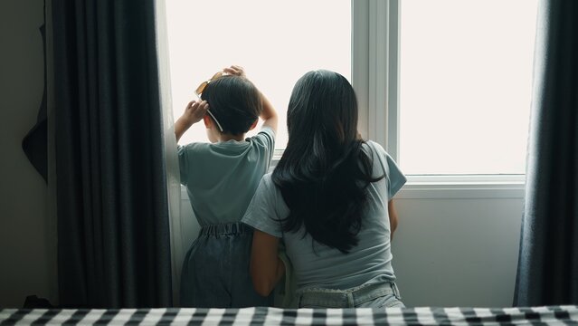 Mother, son wearing sunglasses, gazing through home window