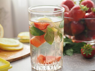 woman making refreshing homemade lemonade detox drink or cocktail summer with ice. Refreshing vibrant summer drinks with lemon, strawberry and mint and colorful straws on the table