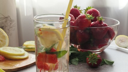 woman making refreshing homemade lemonade detox drink or cocktail summer with ice. Refreshing vibrant summer drinks with lemon, strawberry and mint and colorful straws on the table