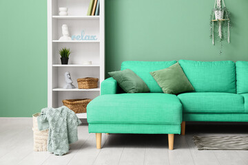 Interior of living room with green cushions on sofa and shelf unit