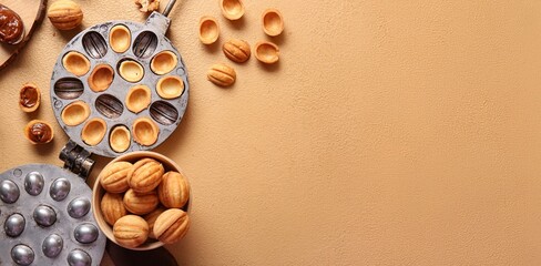 Bowl with tasty walnut shaped cookies and baking form on beige background with space for text