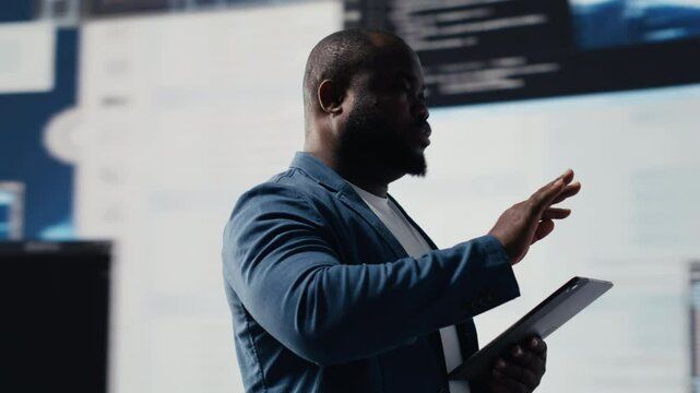 Black software expert focusing on programming language for innovation, reading binary code on terminal window. Reviews code development for data science. Modern futuristic coding life. Camera B.