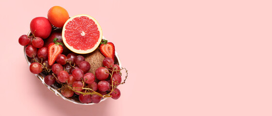 Wicker bowl with different fresh fruits on pink background