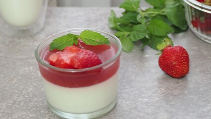 Vanilla panna cotta with strawberry layer in a small portioned vase and fruit pieces in wineglasses. Delicious Italian dessert. low calorie dessert healthy eating diet. woman cooking at home