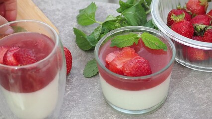 Vanilla panna cotta with strawberry layer in a small portioned vase and fruit pieces in wineglasses. Delicious Italian dessert. low calorie dessert healthy eating diet. woman cooking at home