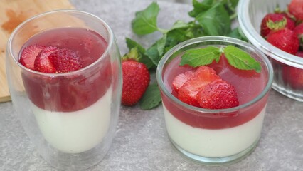 Vanilla panna cotta with strawberry layer in a small portioned vase and fruit pieces in wineglasses. Delicious Italian dessert. low calorie dessert healthy eating diet. woman cooking at home