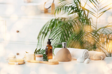 Massage body brushes, bottles and jars with cosmetic products on table in bathroom