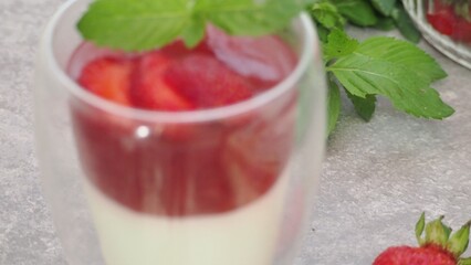 Vanilla panna cotta with strawberry layer in a small portioned vase and fruit pieces in wineglasses. Delicious Italian dessert. low calorie dessert healthy eating diet. woman cooking at home