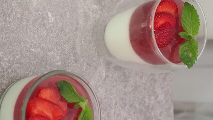 Vanilla panna cotta with strawberry layer in a small portioned vase and fruit pieces in wineglasses. Delicious Italian dessert. low calorie dessert healthy eating diet. woman cooking at home