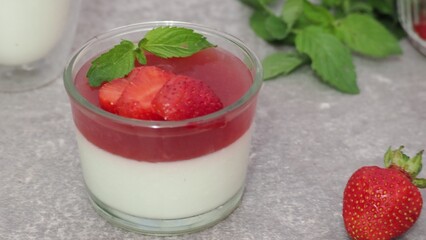 Vanilla panna cotta with strawberry layer in a small portioned vase and fruit pieces in wineglasses. Delicious Italian dessert. low calorie dessert healthy eating diet. woman cooking at home