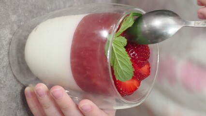 Vanilla panna cotta with strawberry layer in a small portioned vase and fruit pieces in wineglasses. Delicious Italian dessert. low calorie dessert healthy eating diet. woman cooking at home