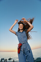 lifestyle woman in modern boho-western denim outfit enjoys carefree moment by the sea with natural...