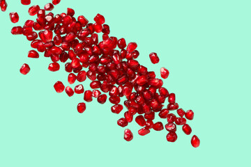 Flying fresh pomegranate seeds on turquoise background