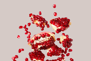 Flying fresh pomegranates with seeds on grey background